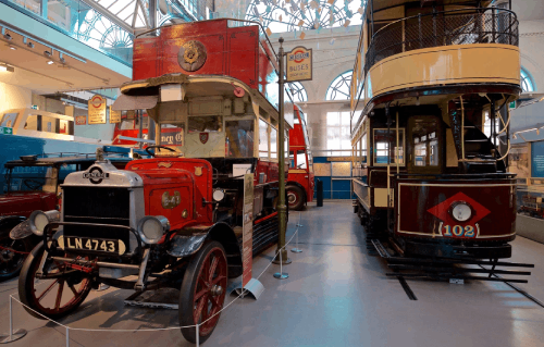 Family exploring a vintage red London bus at the Transport Museum
