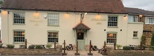 The Pheasant Inn at Longford, a cream painted roadside pub with its name lettered on the wall