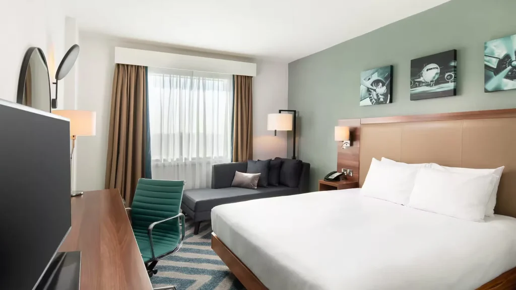 King bedroom at the Hilton Garden Inn at Hatton Cross, with a sofa and aircraft prints above the bed