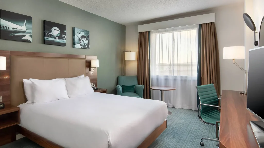 King bedroom at the Hilton Garden Inn at Hatton Cross, with an armchair and aircraft prints above the bed