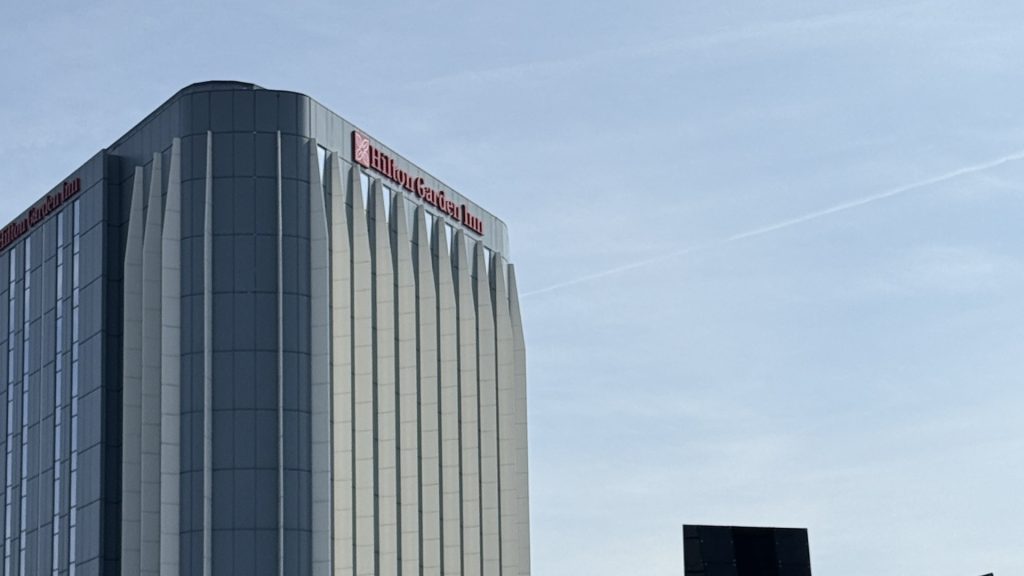 Hilton Garden Inn Heathrow T2 and T3, the full height of the tower with the rooftop sign against the sky