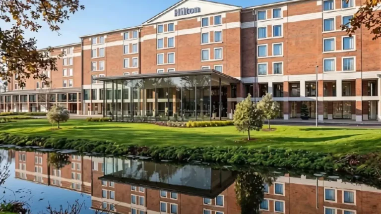 The Hilton London Heathrow Terminal 5 seen across the water, with its glass entrance and the Hilton sign on the roofline