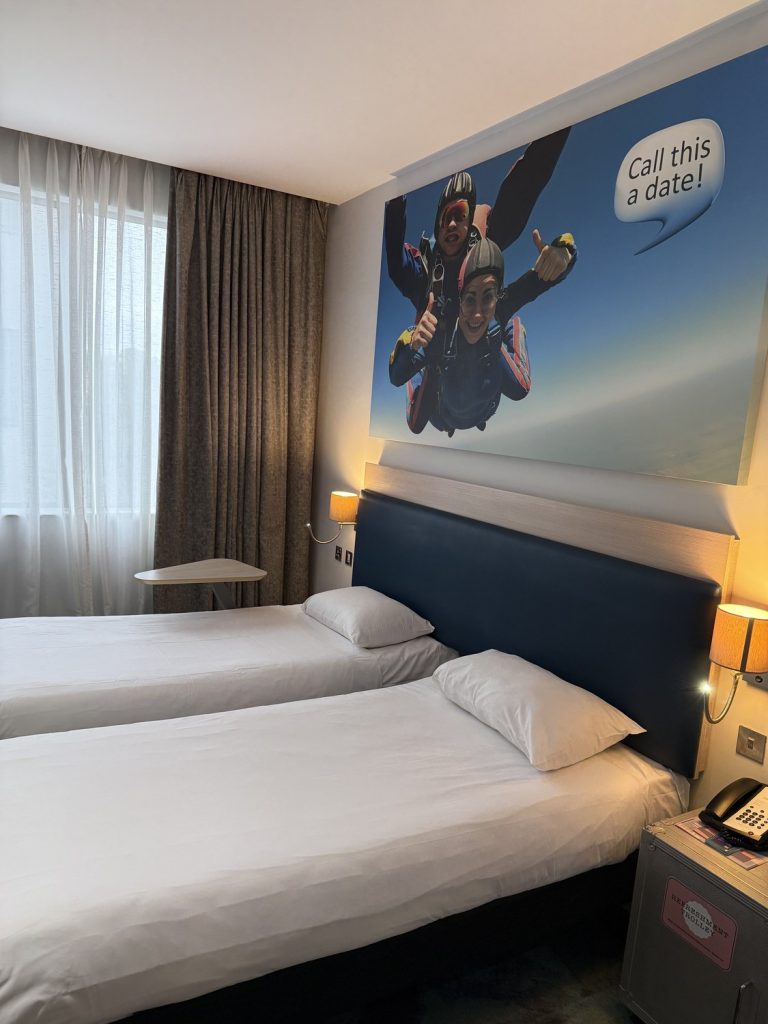 A twin room at ibis Styles Heathrow with a skydiving mural above the beds