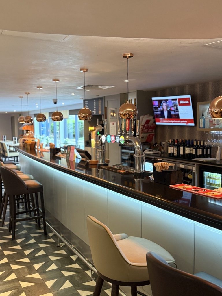 The bar counter, with screens above the bottles