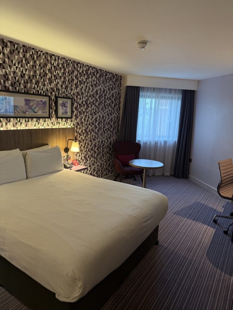 A guest room with a double bed and a seating area by the window