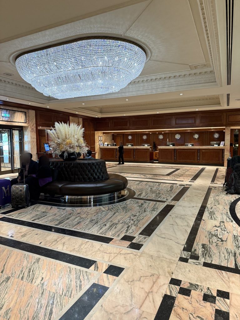 The lobby at the Radisson Blu Edwardian Heathrow, with a chandelier above the marble floor and the reception desks behind