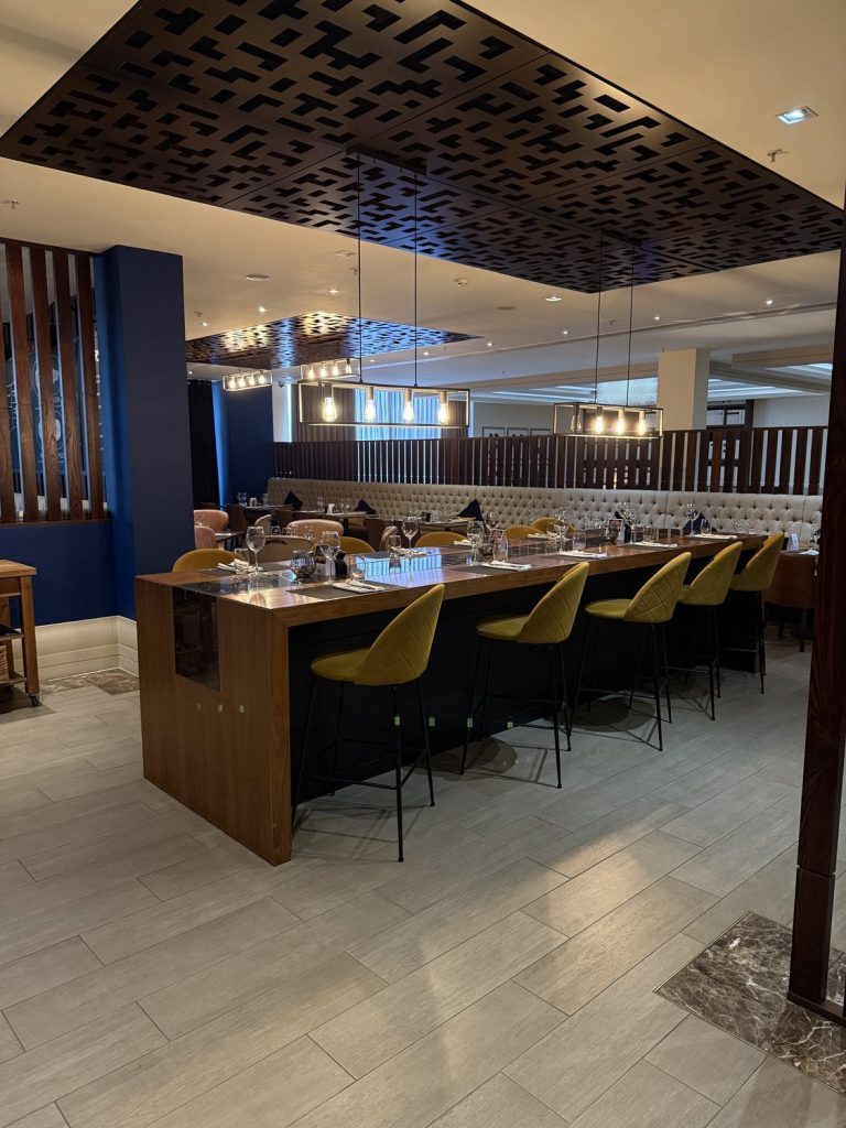 The restaurant counter with high stools under a patterned ceiling