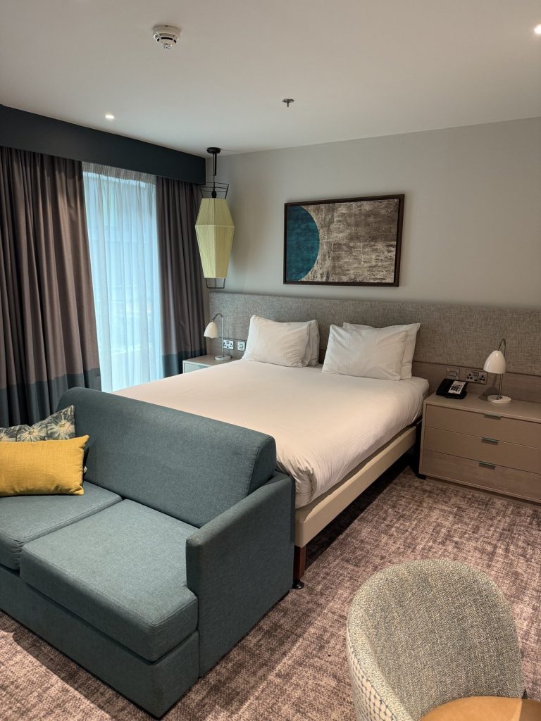 The bedroom area of a suite, with a sofa beside the bed