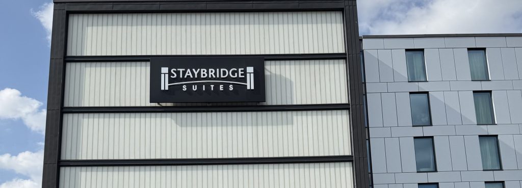 The Staybridge Suites sign on the front of the hotel, seen from the road