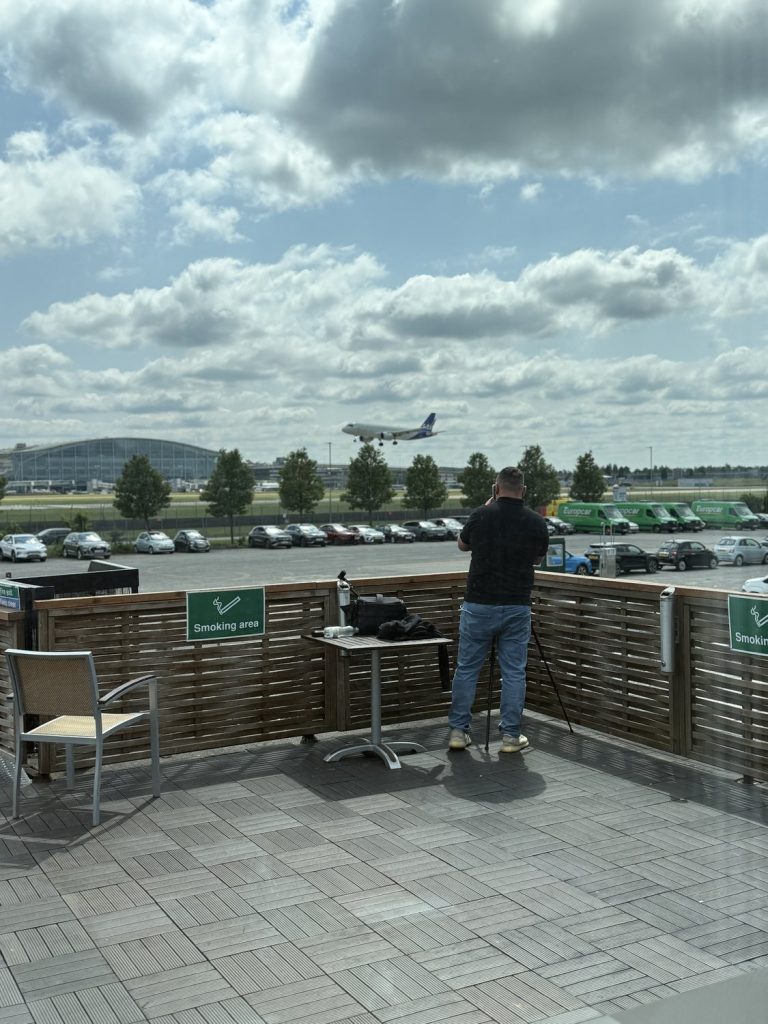 A plane landing at Heathrow seen from the hotel terrace, with the terminal beyond